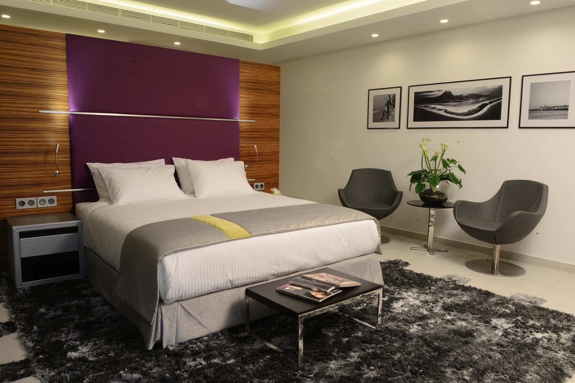 Executive Room features White bed by grey chairs under a purple wall panel near a shaggy rug at Warwick Stone 55 - Beirut