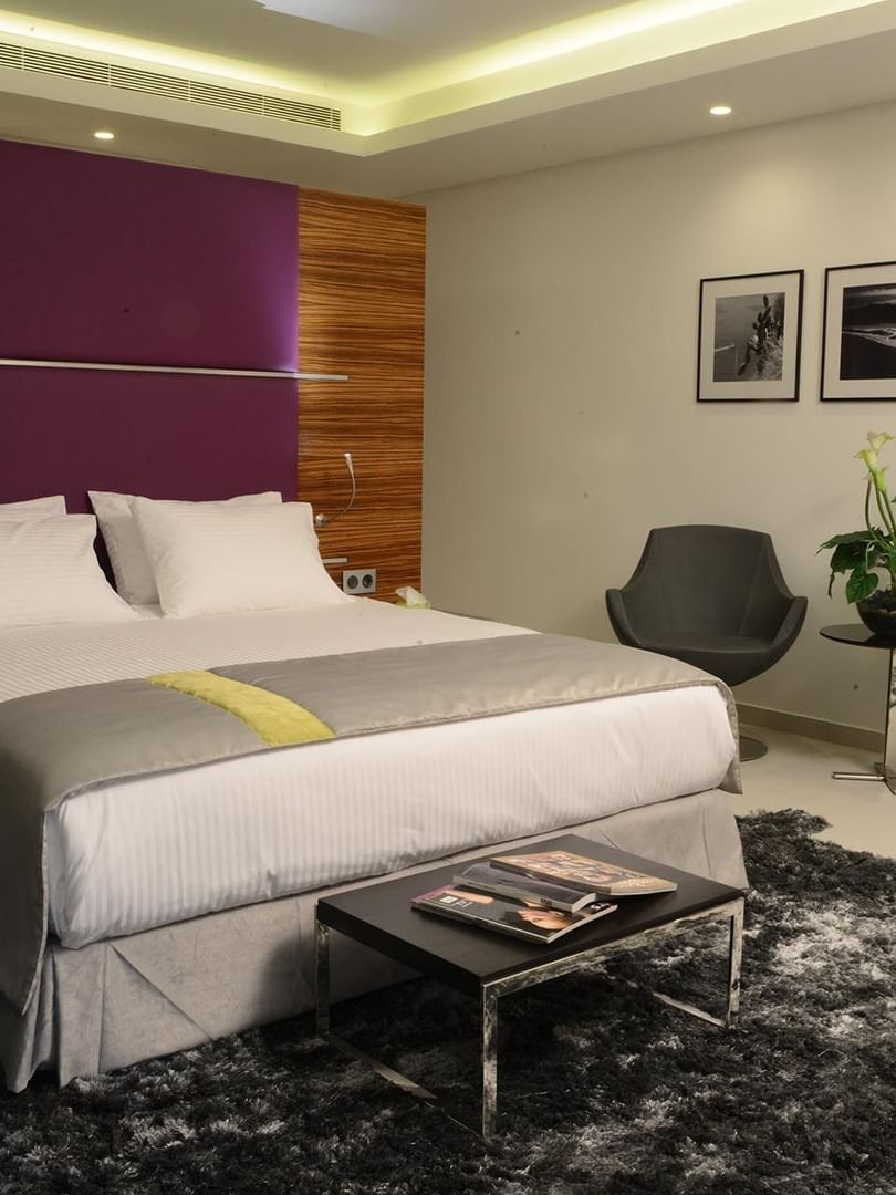 Executive Room features White bed with grey chairs under a purple wall panel near a shaggy rug at Warwick Stone 55 - Beirut
