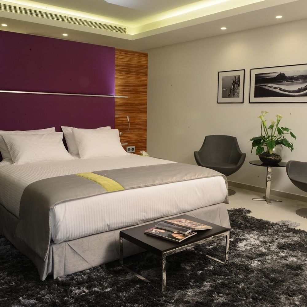 Executive Room features White bed with grey chairs under a purple wall panel near a shaggy rug at Warwick Stone 55 - Beirut