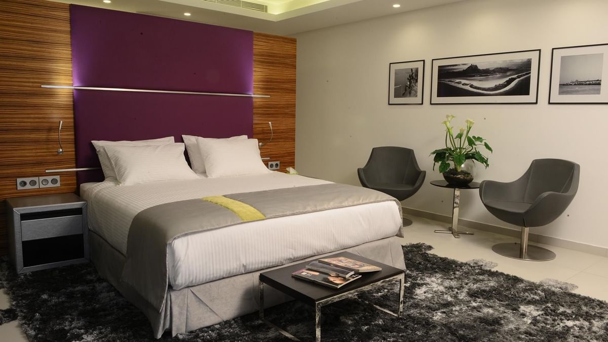 Executive Room features White bed with grey chairs under a purple wall panel near a shaggy rug at Warwick Stone 55 - Beirut