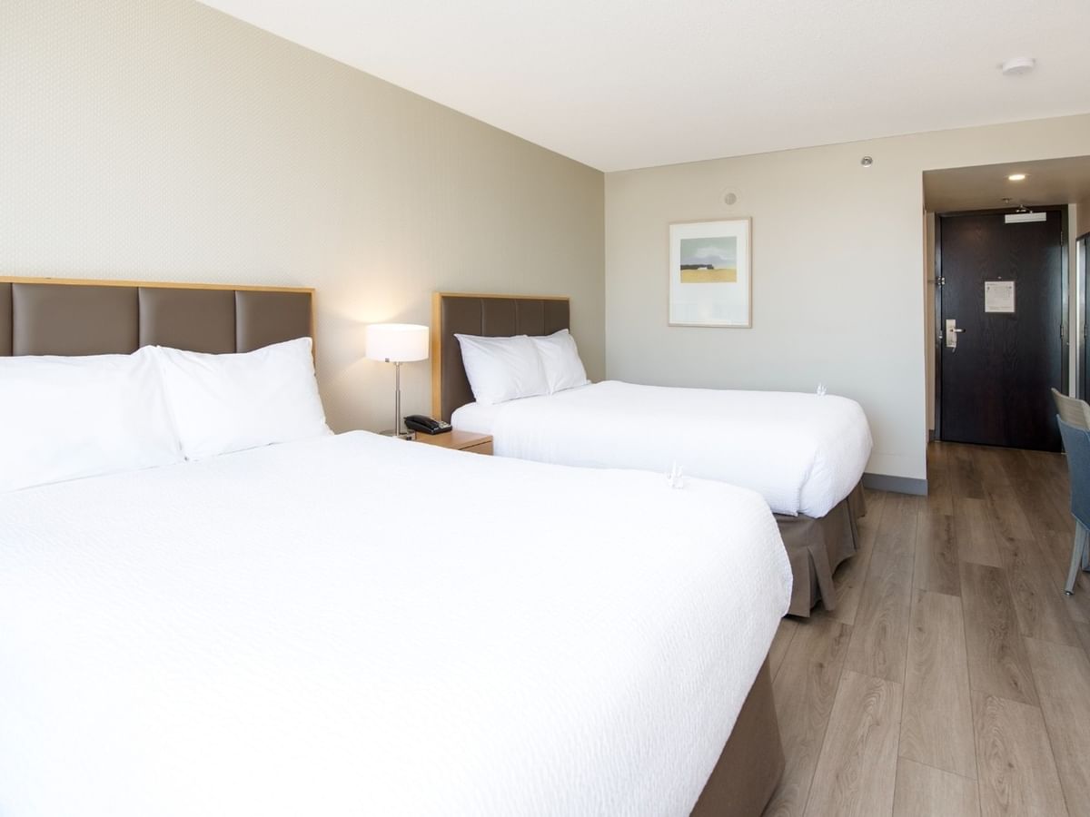 Two beds, desk, chair in our hotel room with wooden floors.