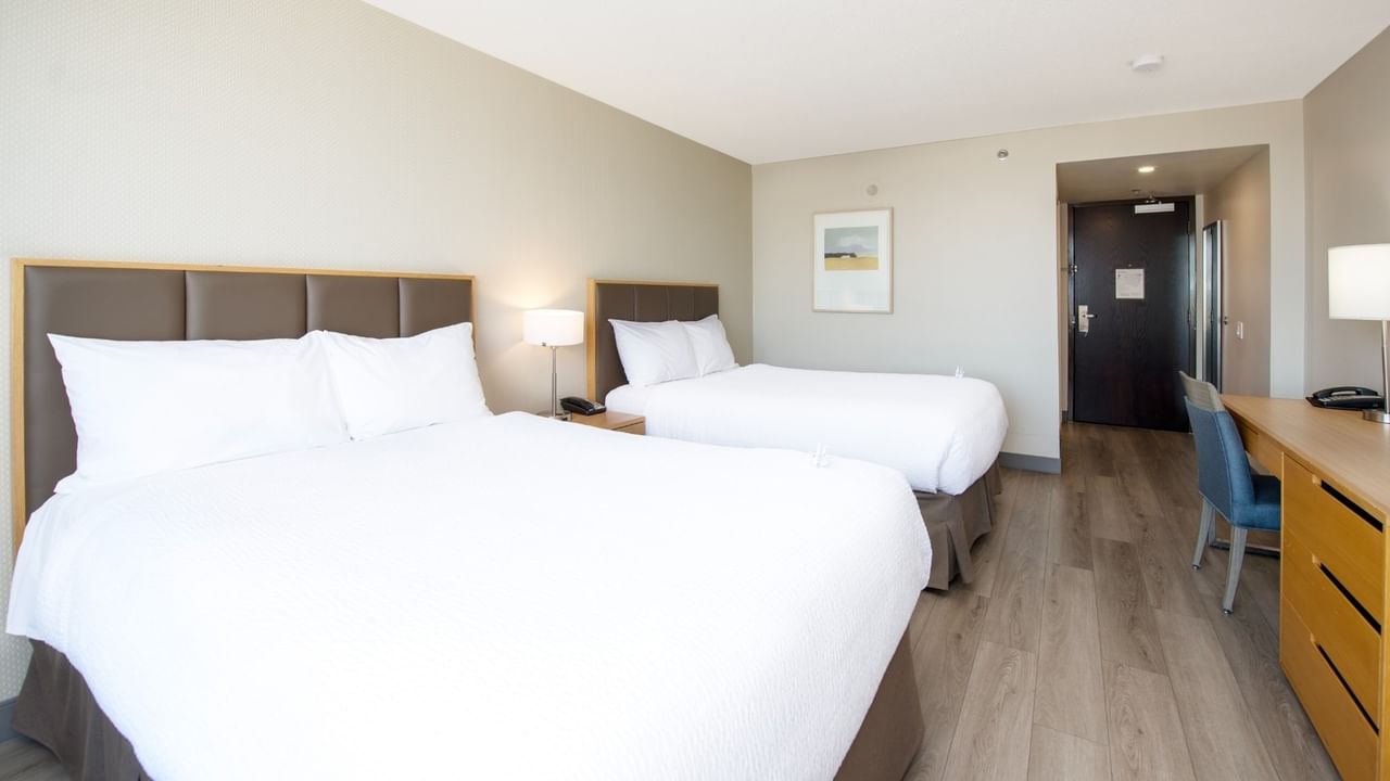 Two beds, desk, chair in our hotel room with wooden floors.
