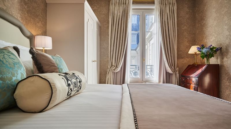 Deluxe Room featuring plush pillows, a lamp, and a window at Hôtel Westminster - Paris