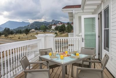 Breakfast table on an outdoor balcony at The Stanley Hotel, with a view of the mountains and a white building
