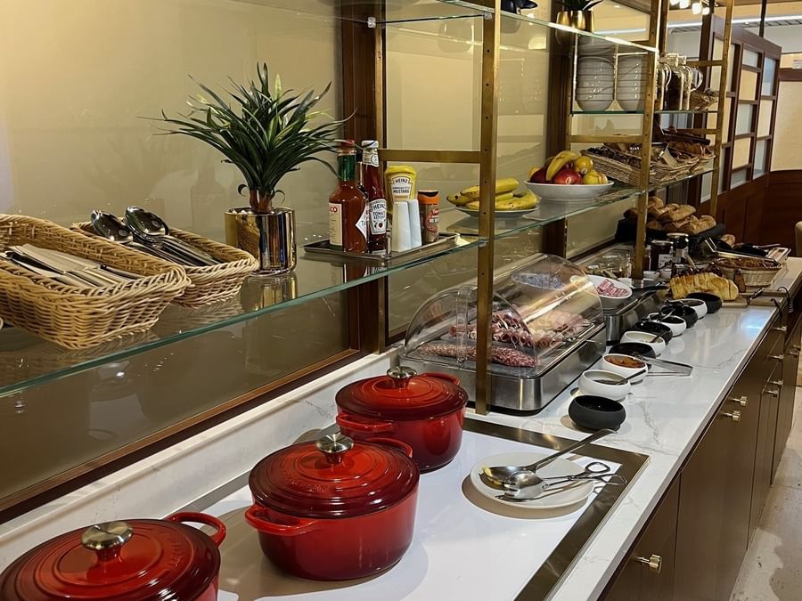 Buffet élégant avec vaisselle et plats variés présentés sur des étagères en verre chez Hôtel Le Yachtman.