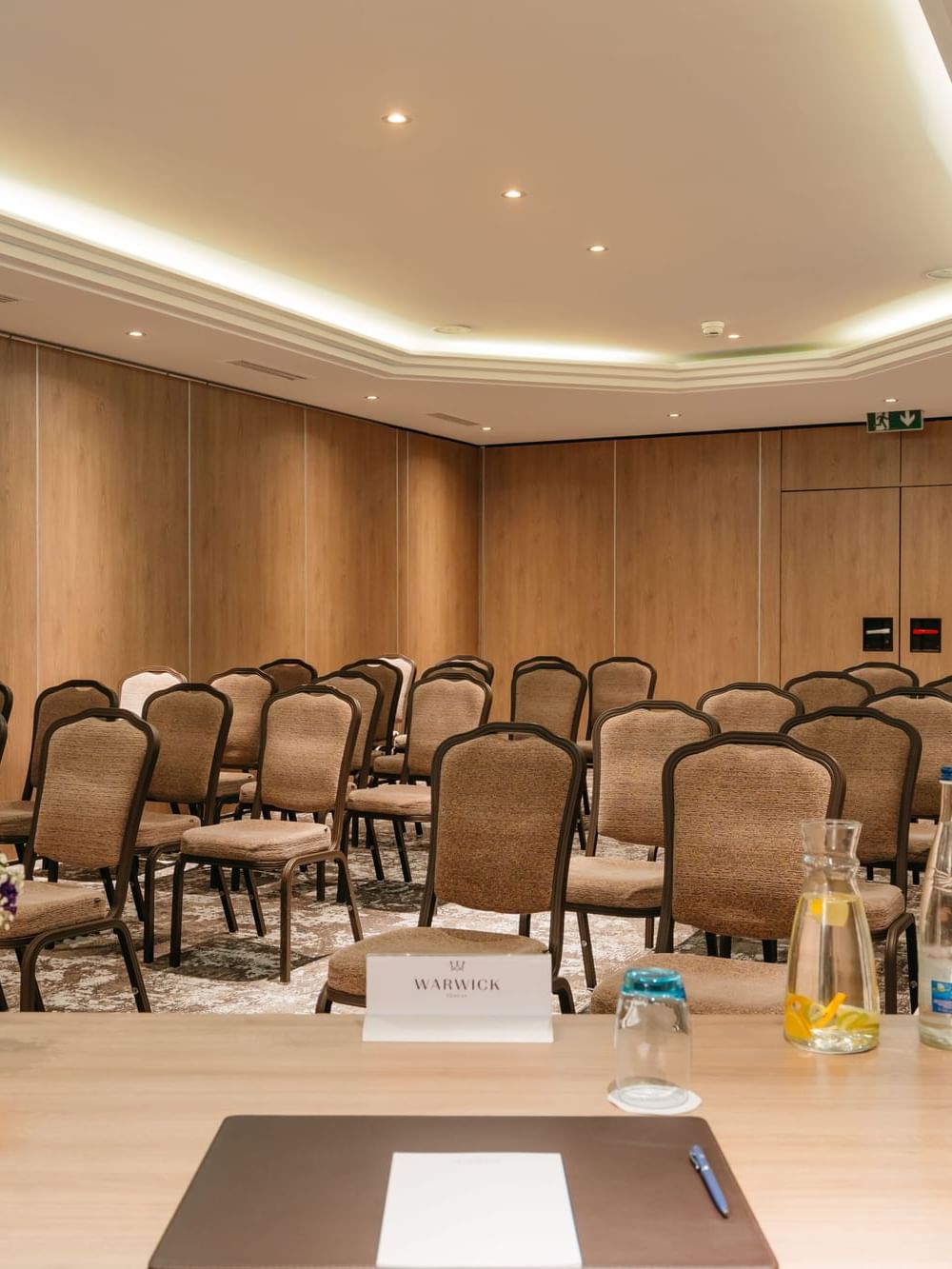Dent-Blanche with Padded chairs in rows by a wooden speaker desk under a recessed ceiling light at Warwick Geneva