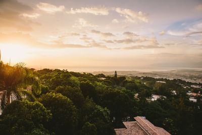 Panoramic hillside view with lush tropical vegetation overlooking the city and coastline at sunset at Hotel Montana Haiti