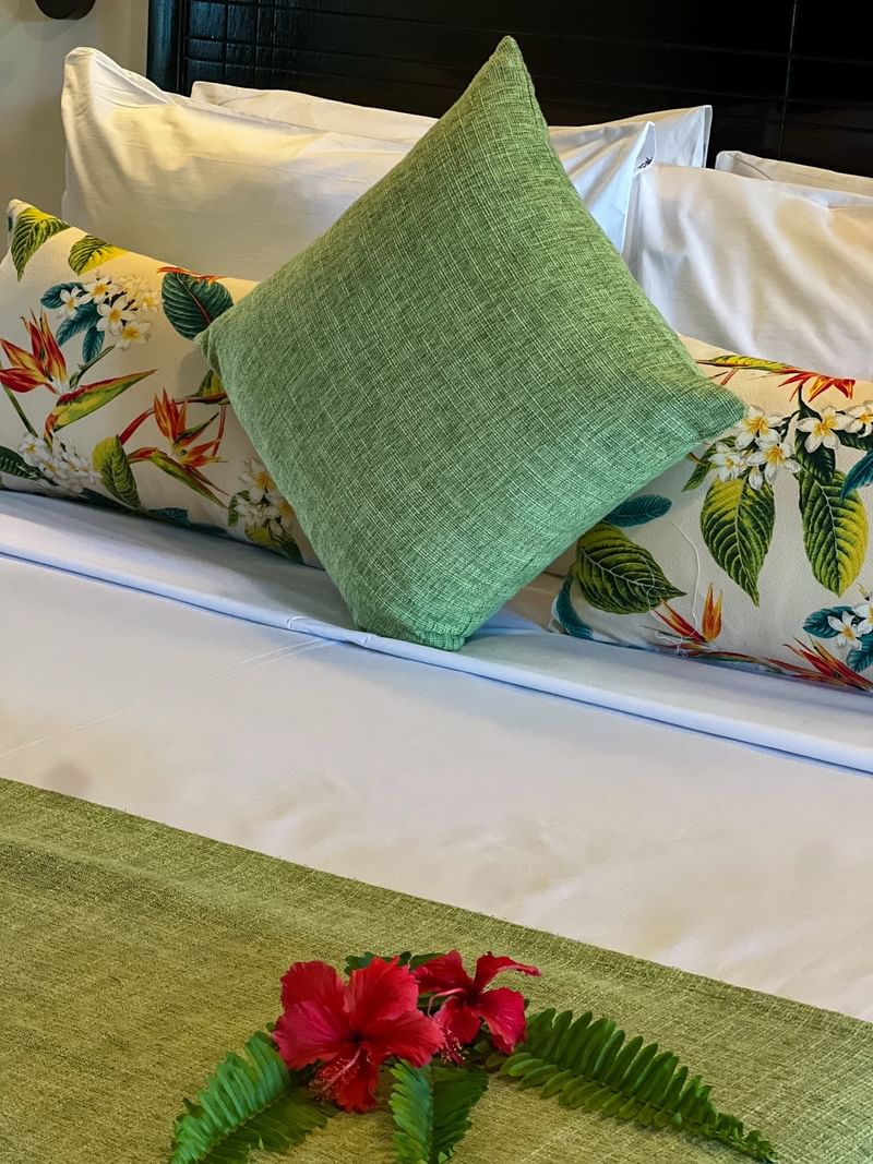 Made bed with floral pillows and flower arrangement at Tokatoka Resort - Fiji International Airport, Nadi.