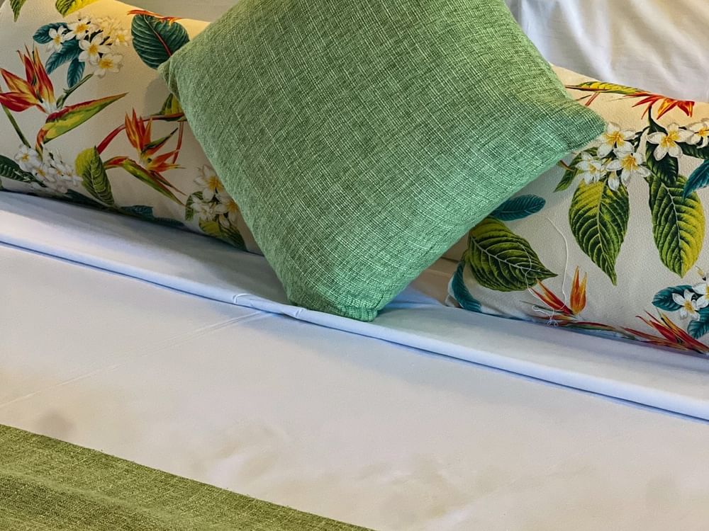 Floral pillows featuring bird of paradise designs by a solid green cushion in Deluxe Villa at warwick Hotels & Resorts