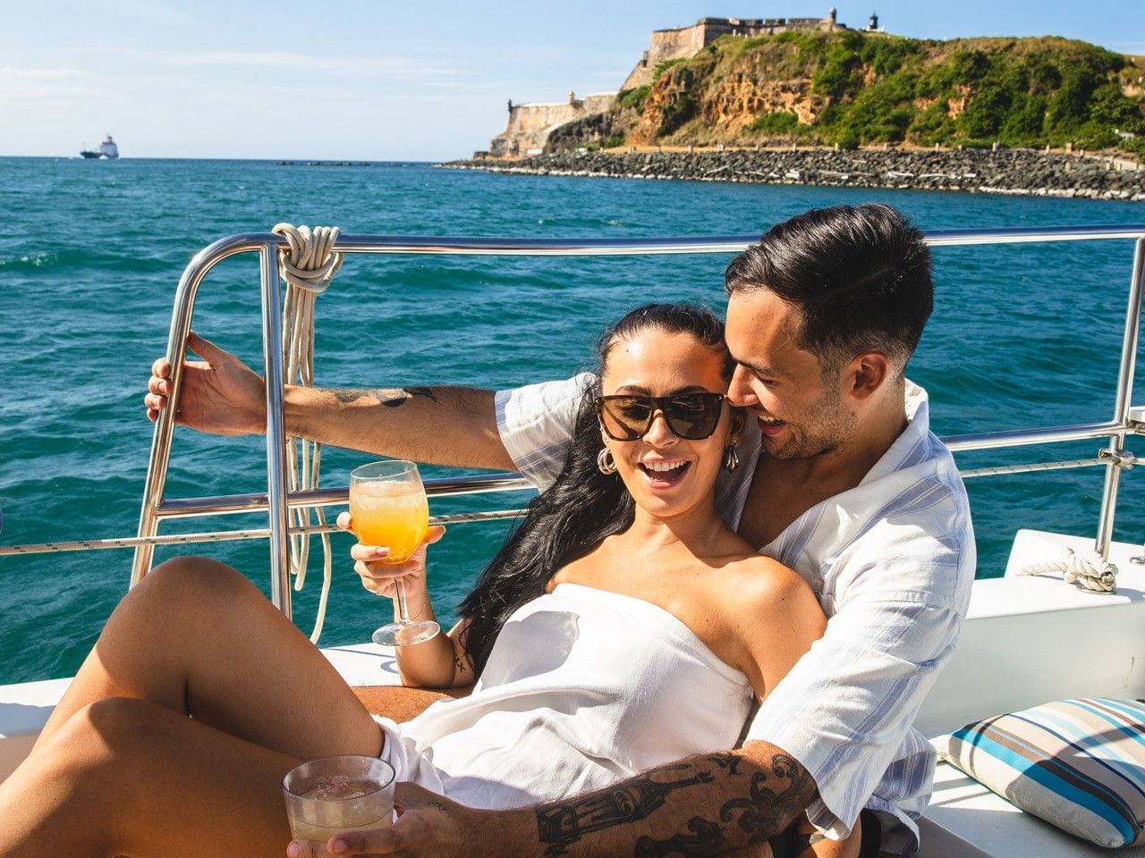 Pareja disfrutando de un catamarán de lujo al atardecer.