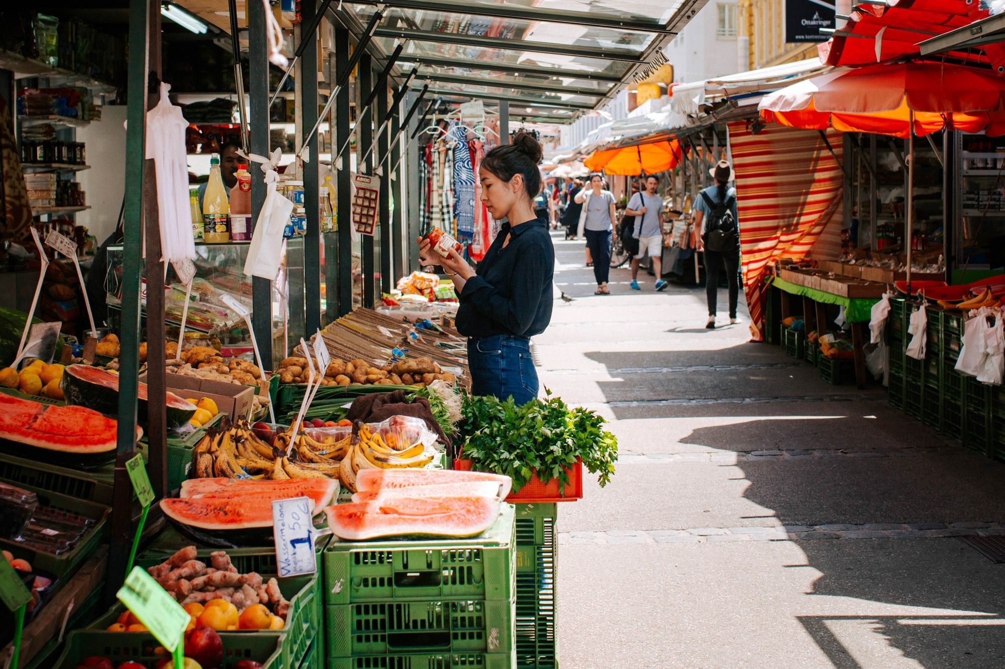 Brunnenmarkt in Vienna with fresh fruit, vegetables and a market visitor browsing lively stalls