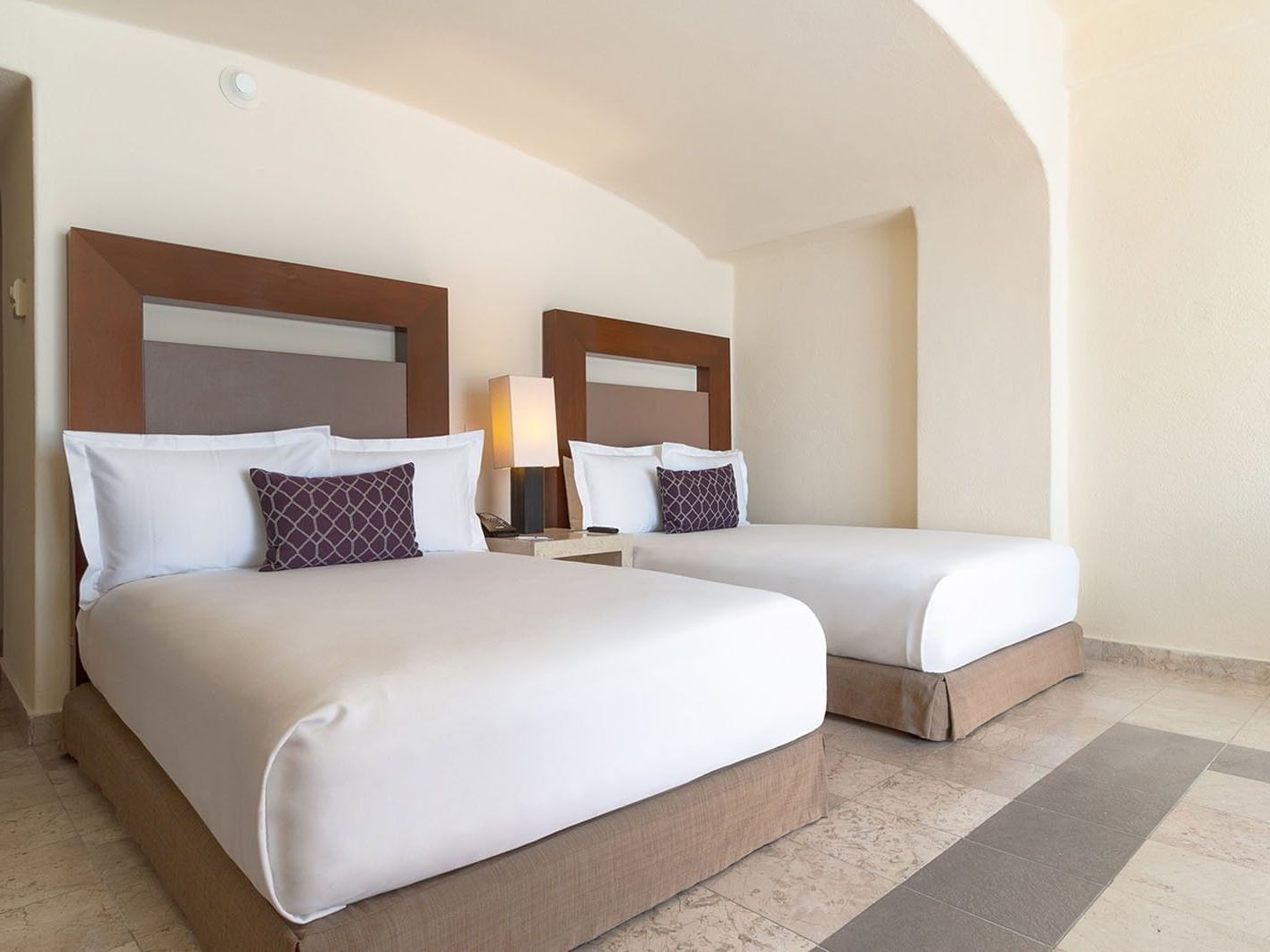 Beds with white linens & purple throw pillows in Partial Ocean View 2 Double Deluxe Room at Camino Real Acapulco Diamante