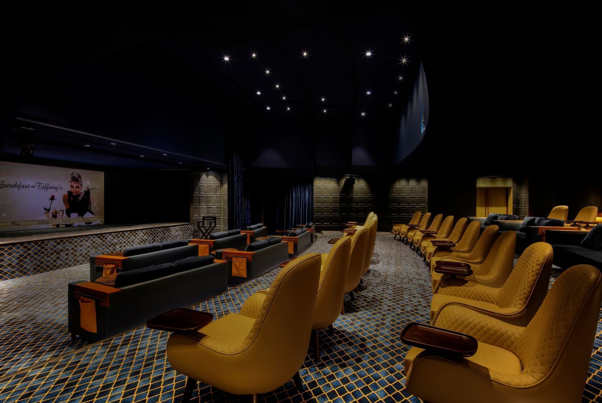 Private dine-in cinema with plush yellow seating and a movie playing on the screen at Paramount Hotel Dubai