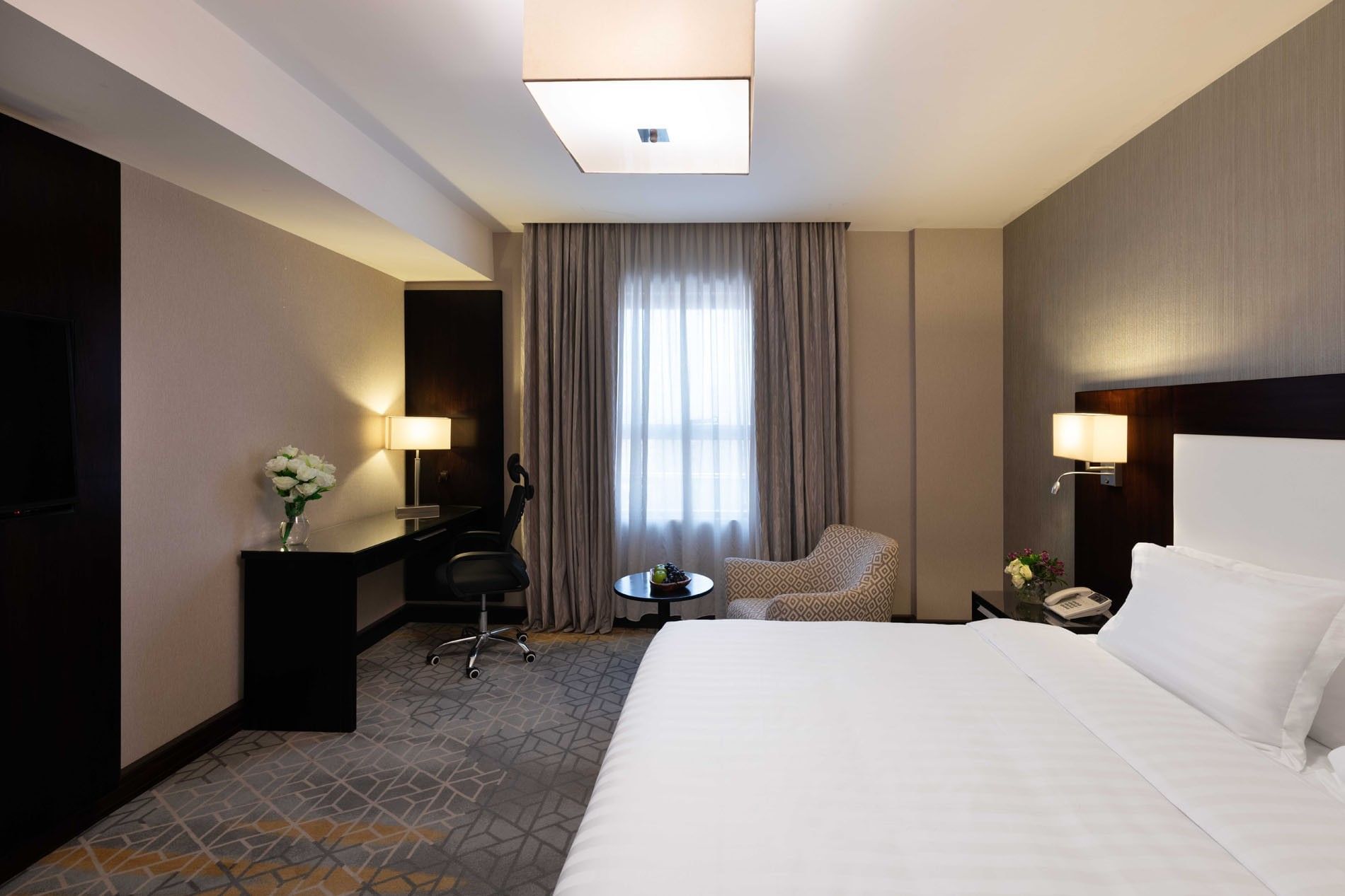 Work desk, nightstand, and cozy lounge chair by the bed in Executive One-Bedroom Suite at Warwick Hotel Jeddah