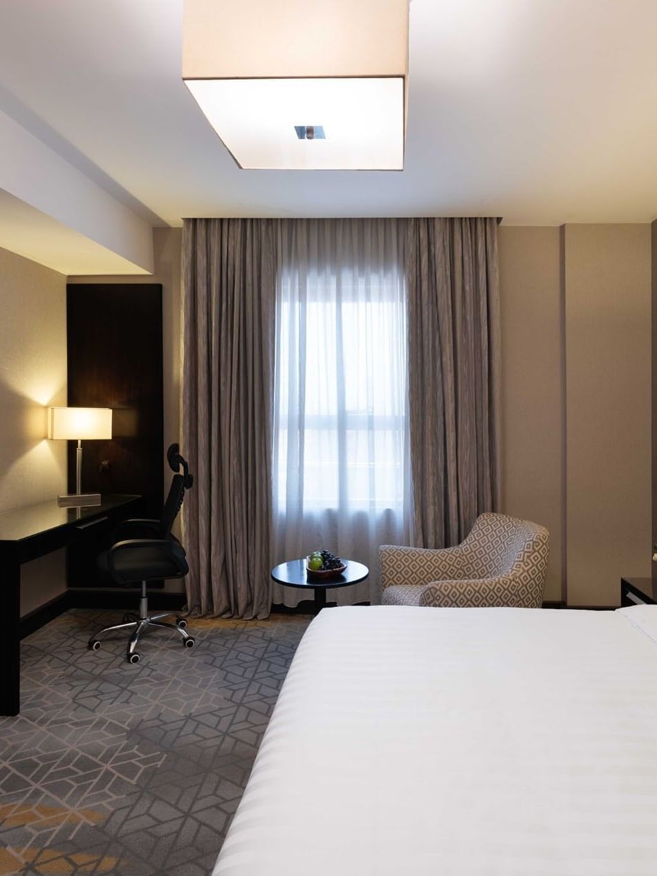 Work desk, nightstand, and cozy lounge chair by the bed in Executive One-Bedroom Suite at Warwick Hotel Jeddah