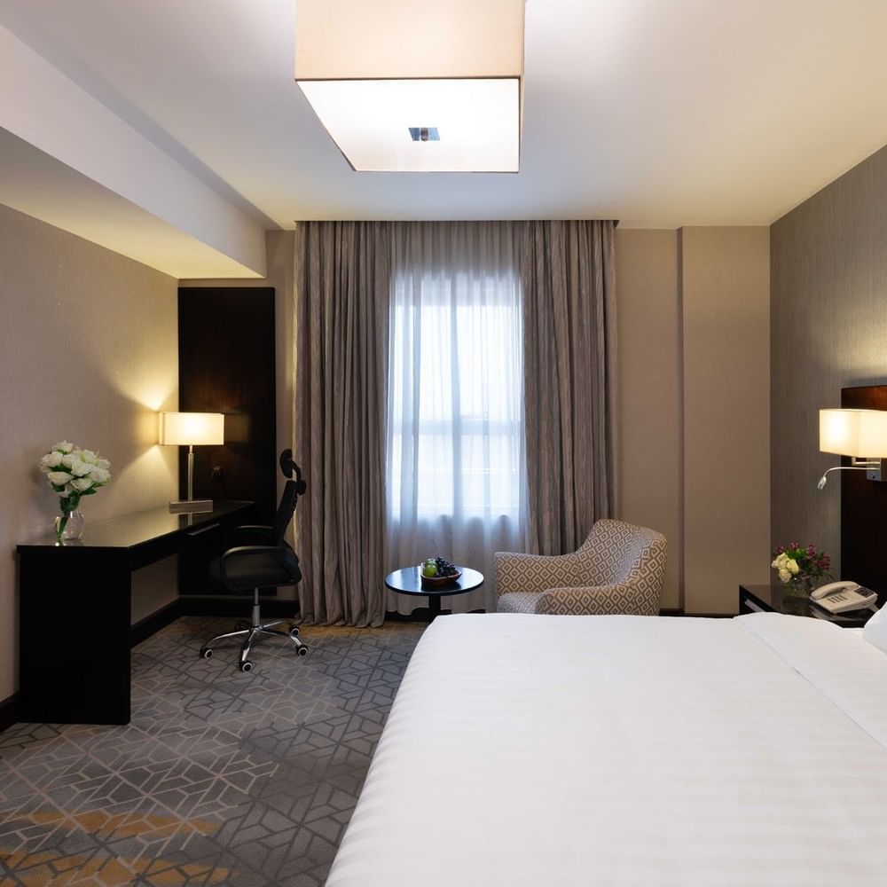 Work desk, nightstand, and cozy lounge chair by the bed in Executive One-Bedroom Suite at Warwick Hotel Jeddah