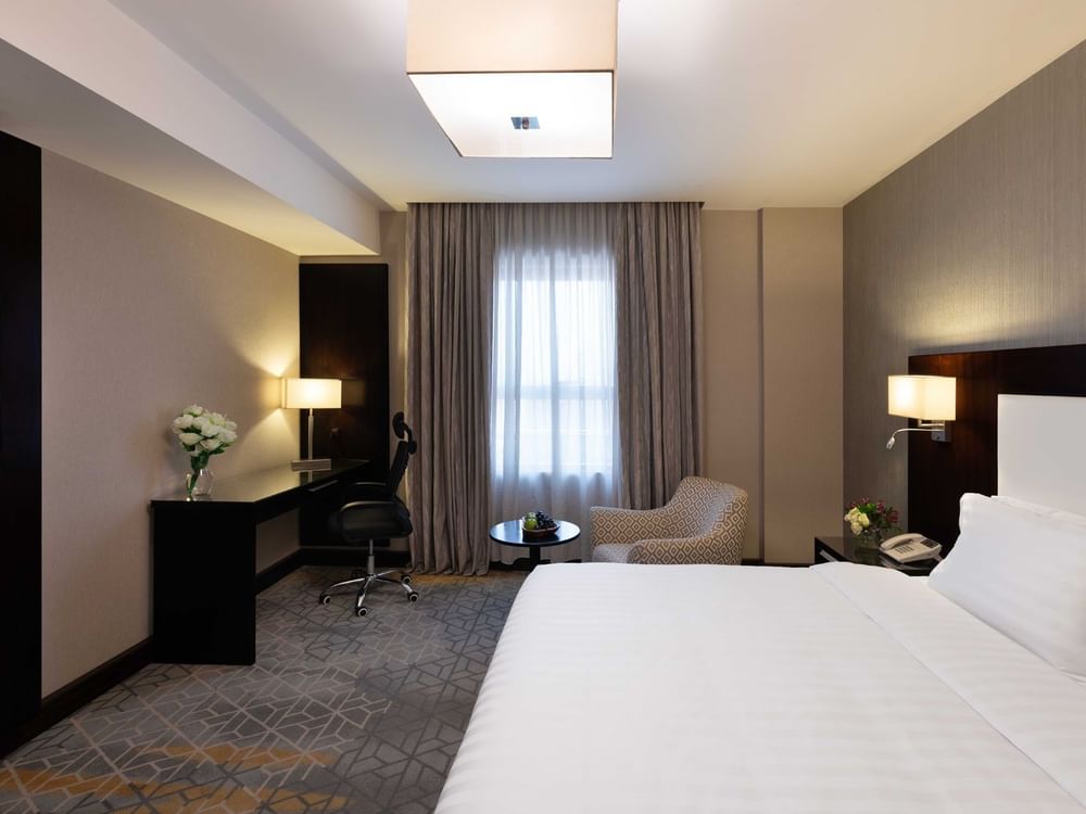 Work desk, nightstand, and cozy lounge chair by the bed in Executive One-Bedroom Suite at Warwick Hotel Jeddah