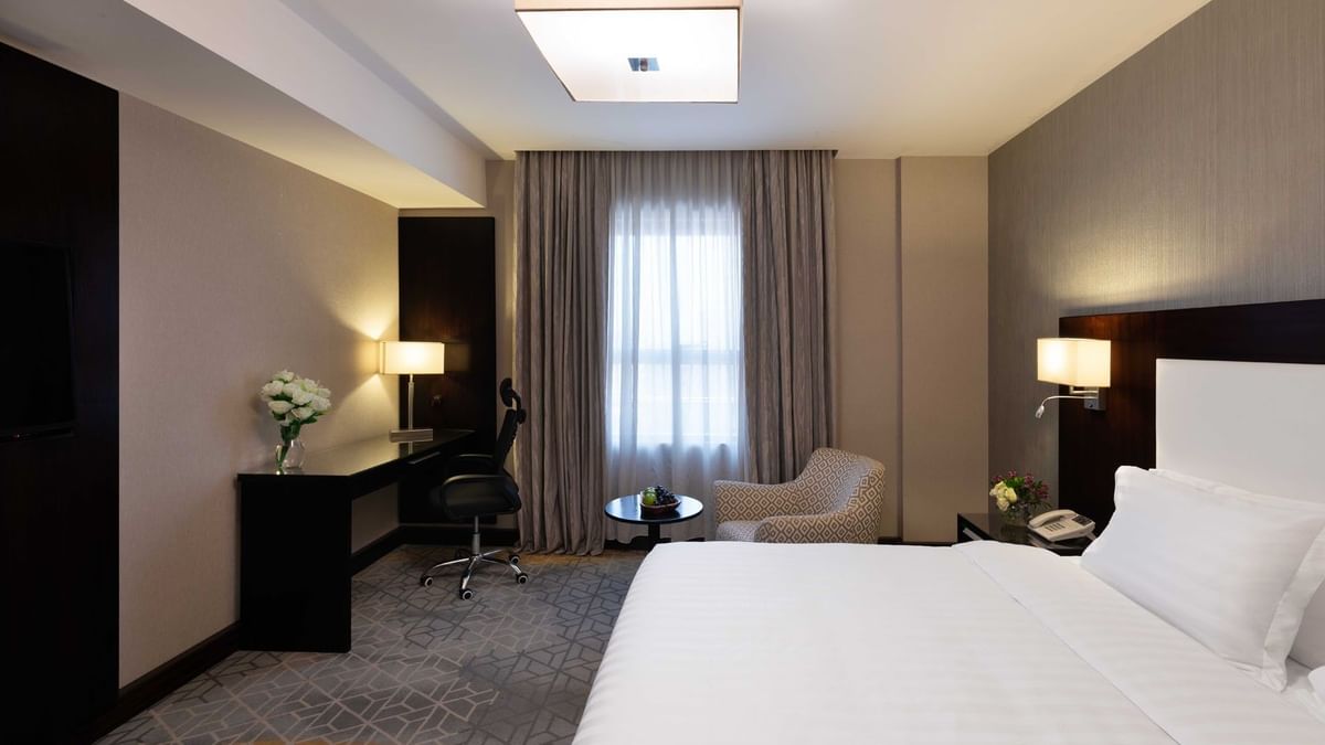 Work desk, nightstand, and cozy lounge chair by the bed in Executive One-Bedroom Suite at Warwick Hotel Jeddah