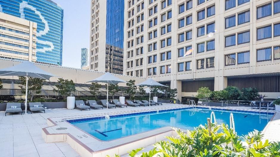 Sun loungers and patio umbrellas by the pool at Sofitel Brisbane Central