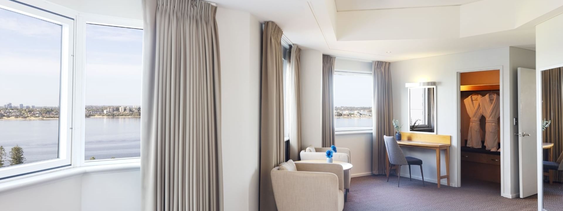 Spacious bed room with a walking wardrobe, sofa, small make up desk and stunning river views