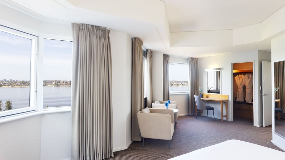 Spacious bed room with a walking wardrobe, sofa, small make up desk and stunning river views