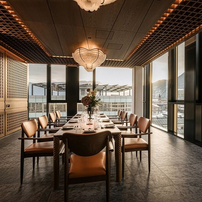 Elegantes Esszimmer mit langem Tisch, Stühlen, großen Fenstern und Blick auf die Stadt.