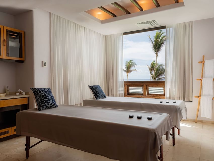 A tranquil spa room with two massage beds and ocean views at Marquis Los Cabos Resort ready for relaxation