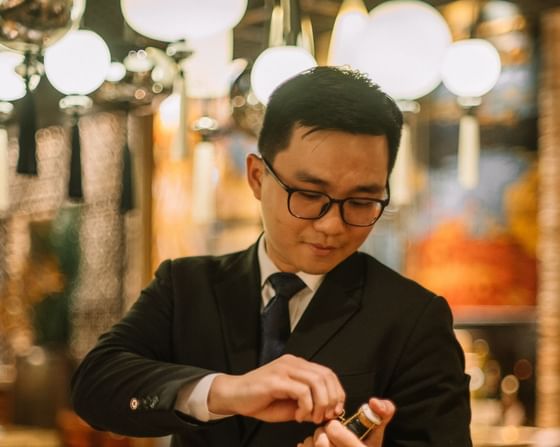 Suited waiter expertly opening a bottle of champagne in Square One Restaurant at Park Hyatt Saigon