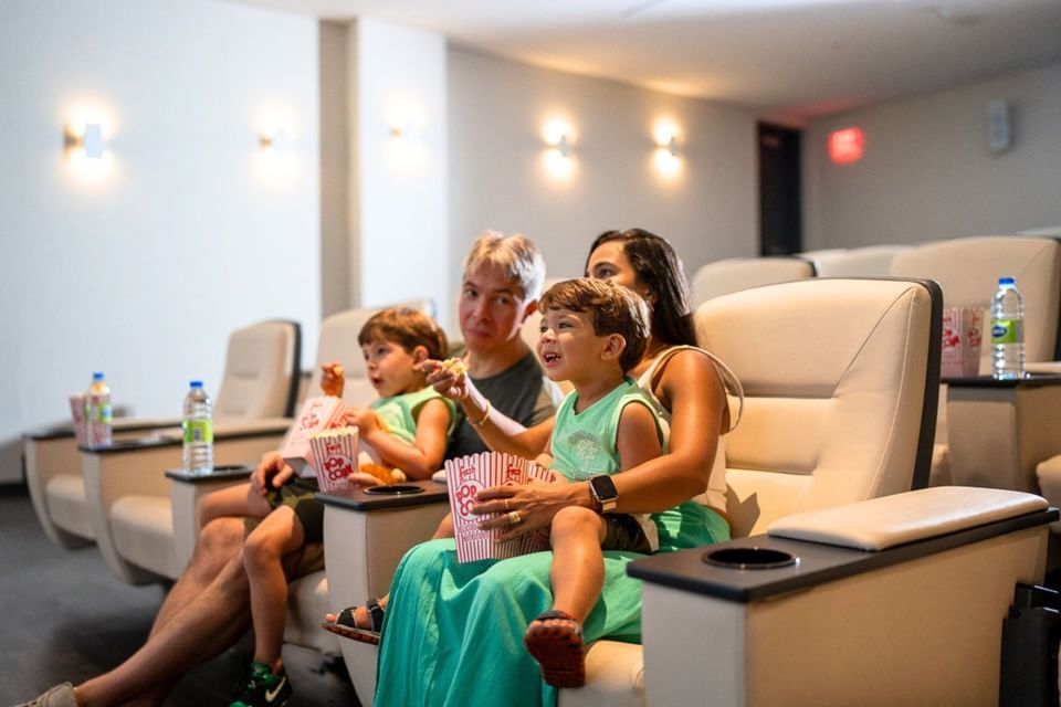 Screening Room with family sharing popcorn in cream cinema seats with cup holder trays at Hotel X Toronto