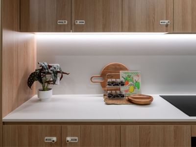 Modern kitchen with wooden cabinets and white countertops at UniLodge Brisbane City.