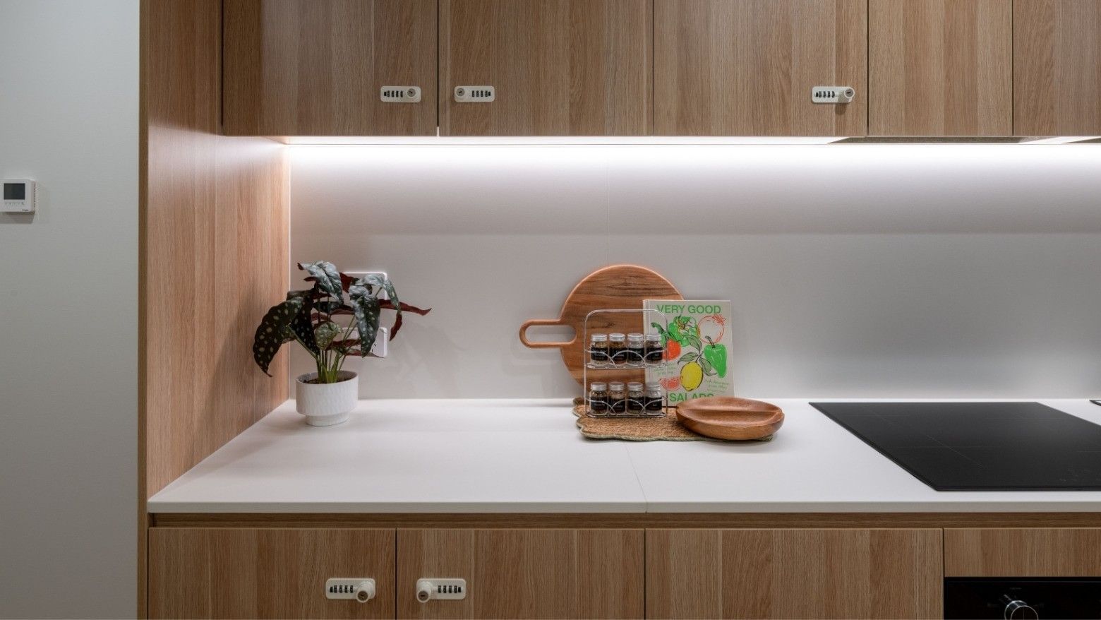 Modern kitchen with wooden cabinets and white countertops at UniLodge Brisbane City.