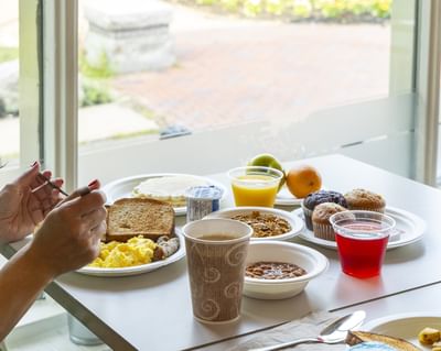 Woman eating eggs & toast, and muffins during a delicious Rodd Moncton breakfast at the Rodd Moncton