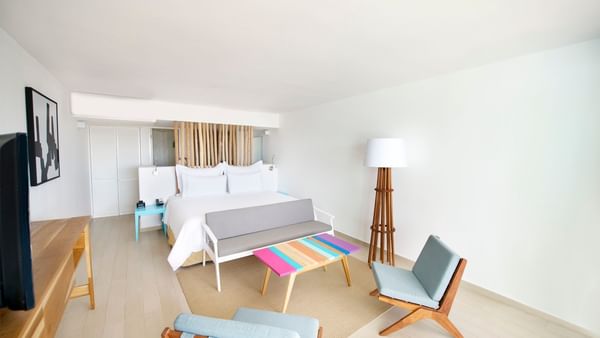 Governor Suite featuring a large bed, colorful bench, and stylish seating at Fiesta Americana