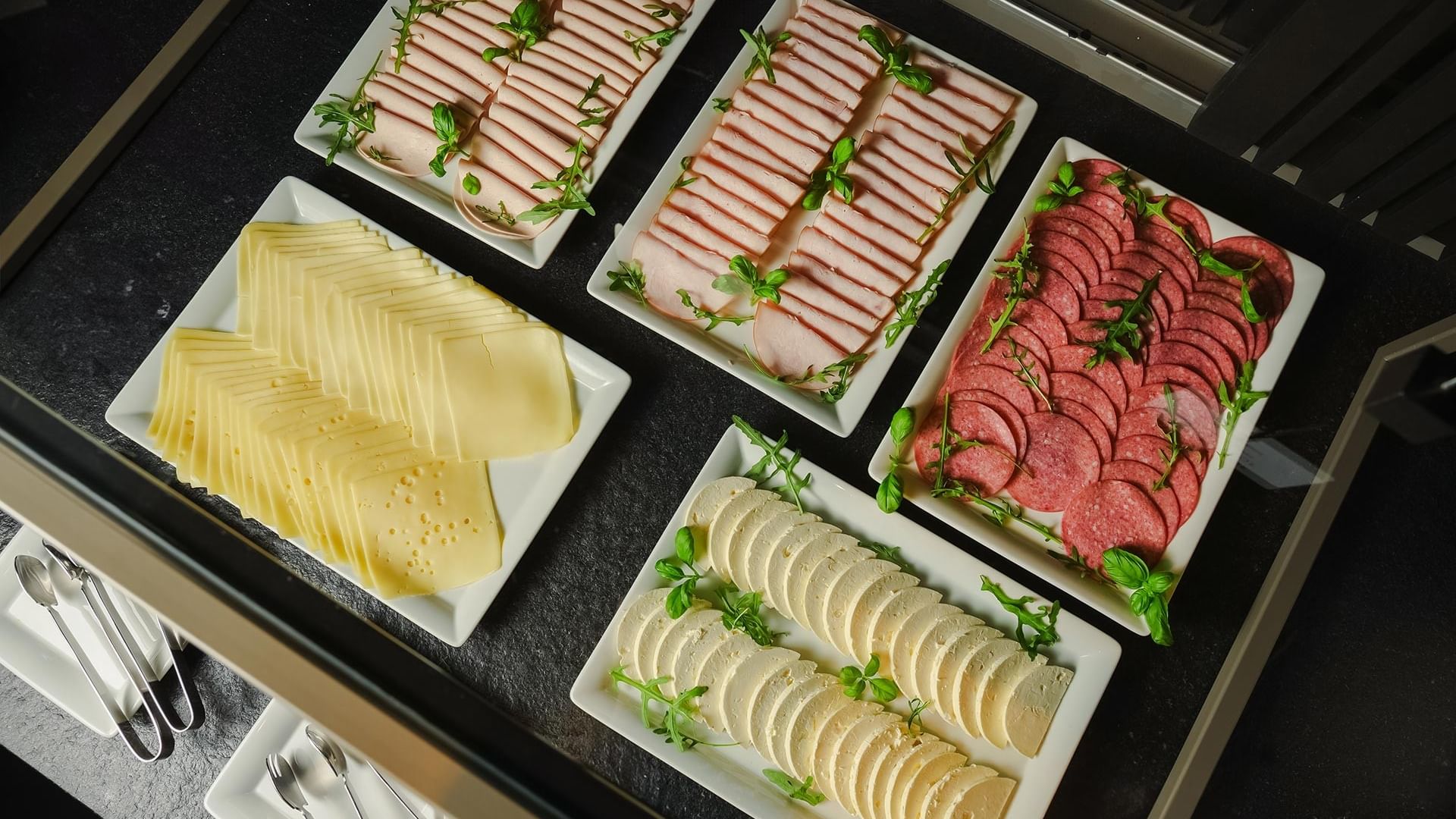 Verschiedene Fleisch- und Käsesorten auf Tellern im Frühstücksrestaurant des Sylter Hof Berlin.