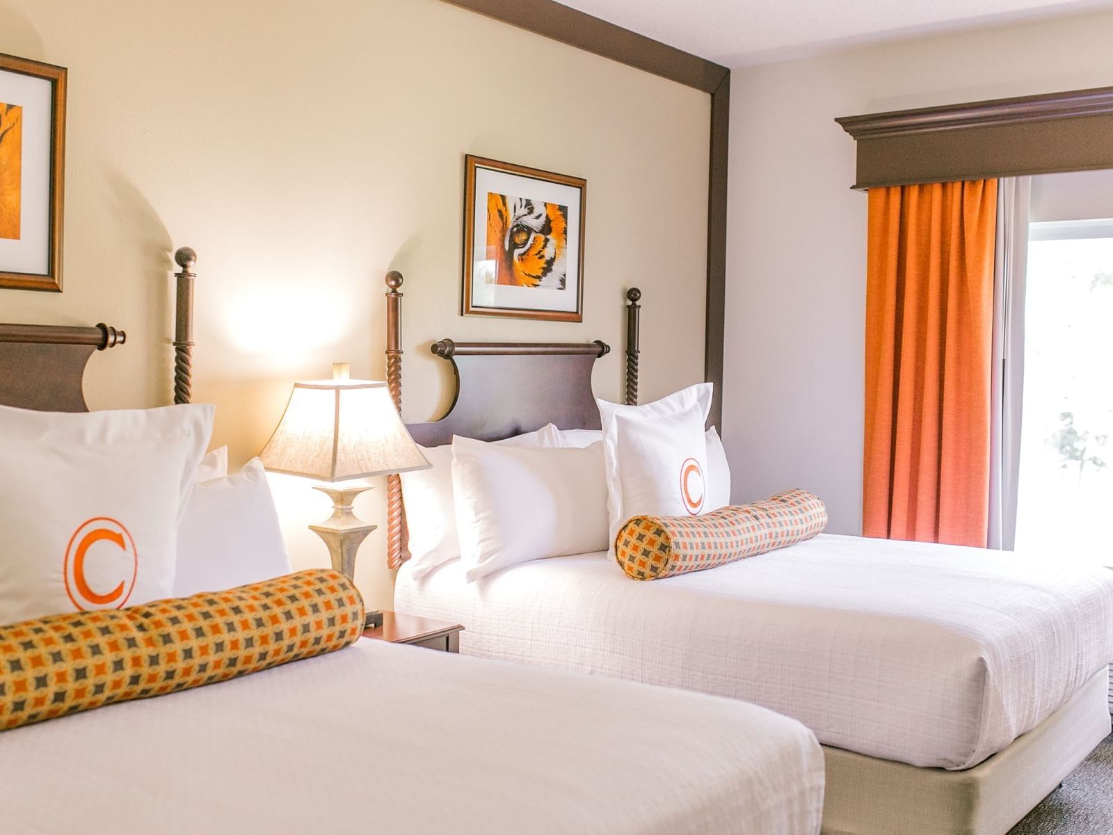 two white beds in hotel room with window and orange curtains