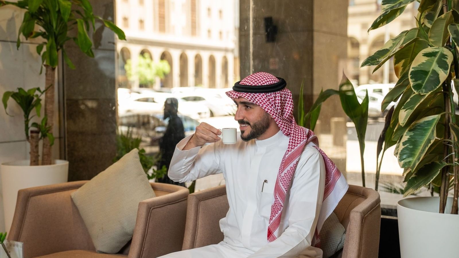 Man in traditional clothing drinking coffee while sitting in Oasis Coffee Shop at Saja Warwick Madinah