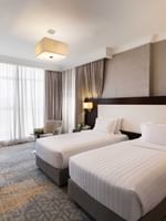 Work desk, nightstand, and cozy lounge chair by the beds in the Deluxe Room at Warwick Hotel Jeddah