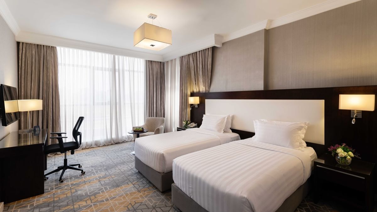 Work desk, nightstand, and cozy lounge chair by the beds in the Deluxe Room at Warwick Hotel Jeddah