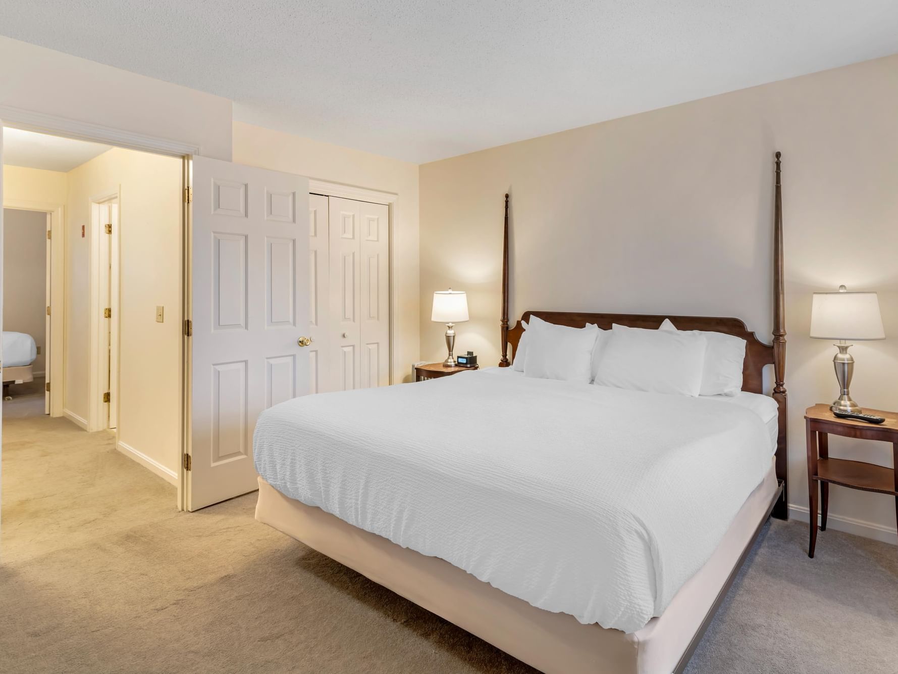 Cozy bedroom with warm lighting & carpeted floors in the King Accessible at Harraseeket Inn