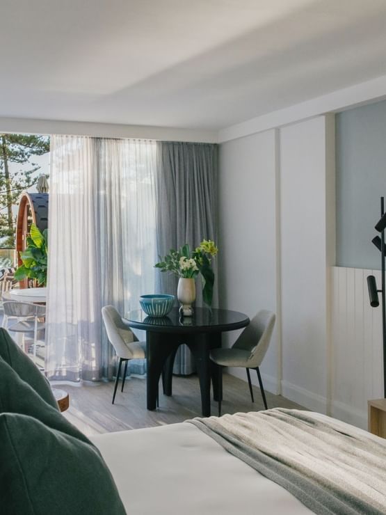 Wellness Suite Twin at Elysium Manly with a bed by a round black dining table, offering cozy Manly accommodation