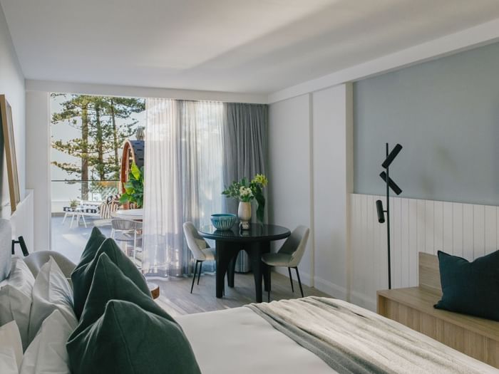 Wellness Two Bedroom Suite at Elysium Manly with a bed by a round black dining table, offering cozy Manly accommodation