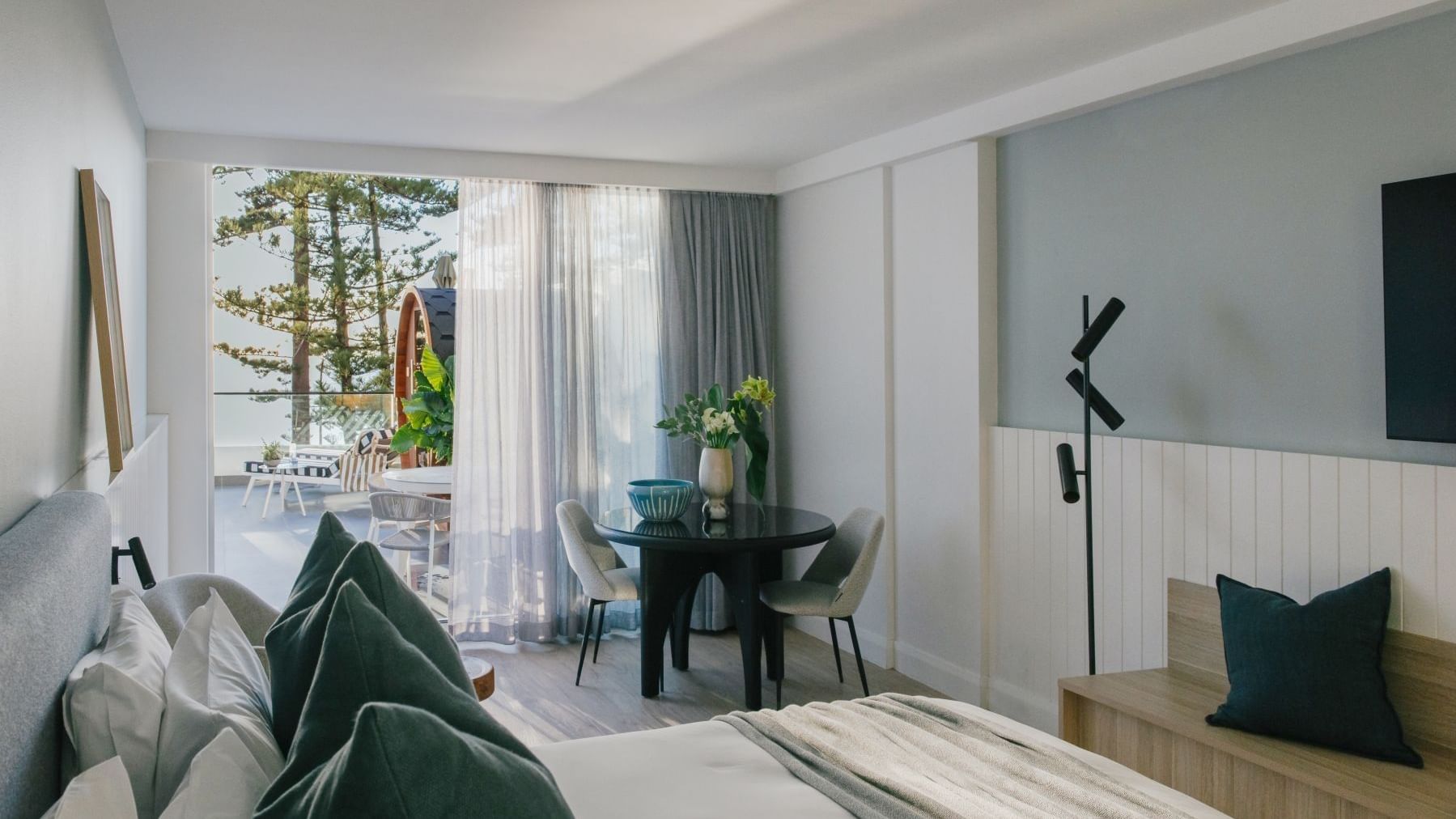 Wellness Two Bedroom Suite at Elysium Manly with a bed by a round black dining table, offering cozy Manly accommodation