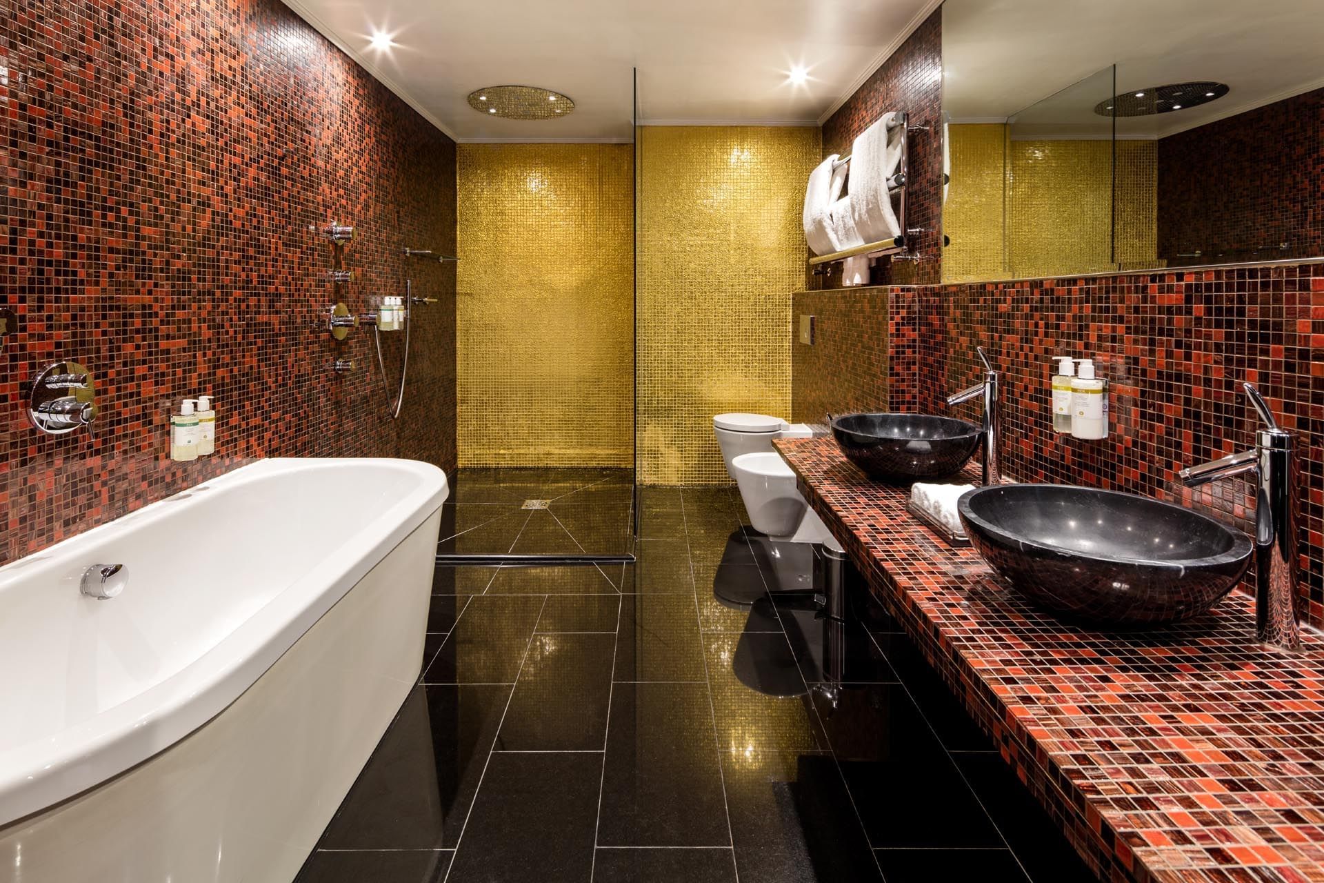 Opium Suite bathroom with red mosaic tiles, a large tub, and dual sinks at The May Fair Hotel