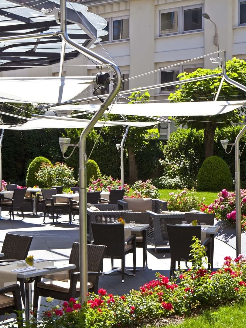 The Lounge Bar & Terrace with wicker chairs and tables, shaded by modern awnings at Warwick Reine Astrid - Lyon