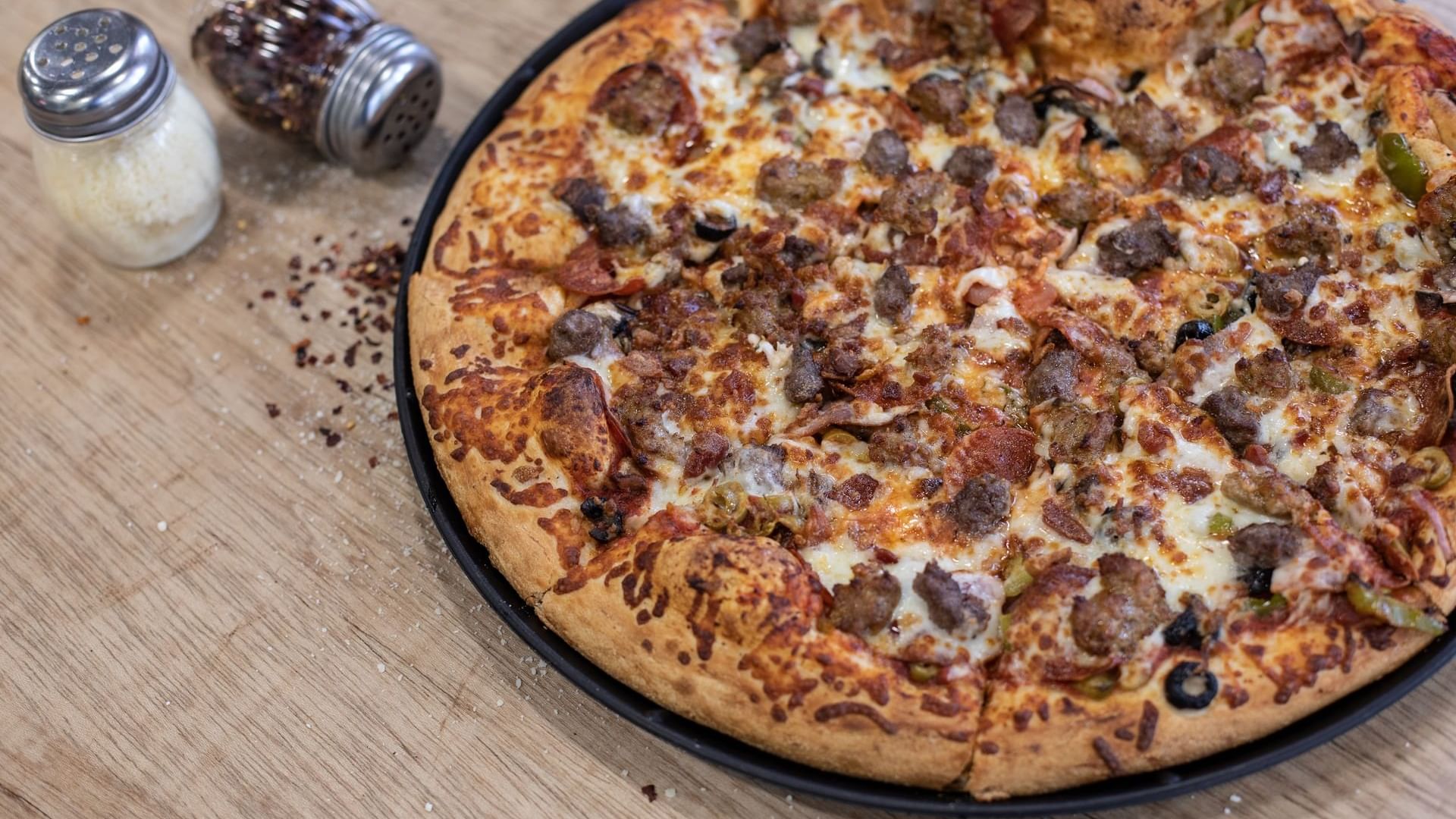 Close-up of Pizza served with salt and pepper in Bruno’s Pizza at Watersound Inn