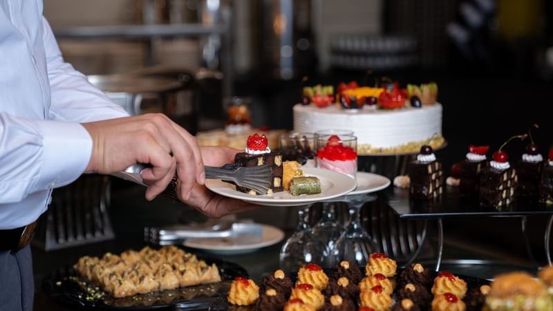 Chef serving a plate of pastries at Al Firdous in Saja by Warwick Madinah.