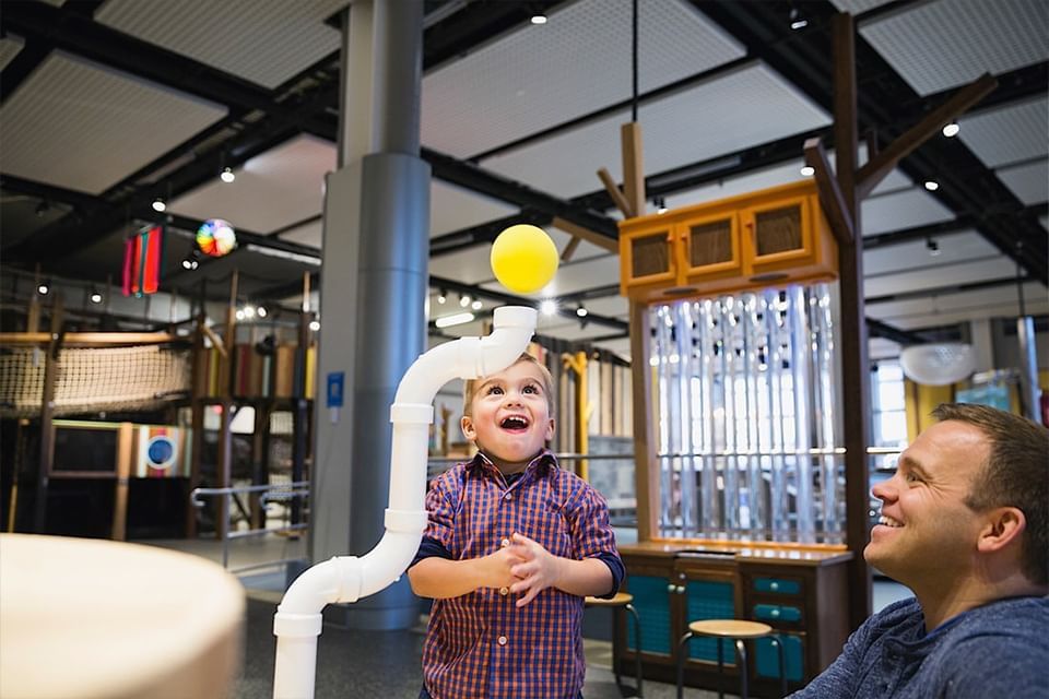 A man and child playing with a ball in Telus Spark Kids Museum near Hotel Clique Calgary Airport