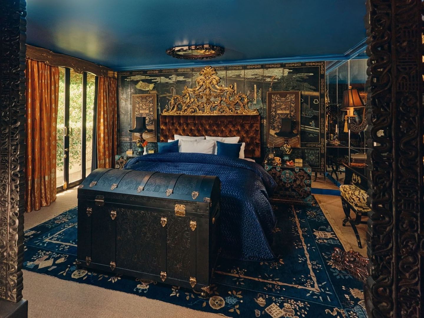 Grand Belle Bleue featuring gold headboard and large antique trunk, with intricate oriental patterns at Petit Ermitage