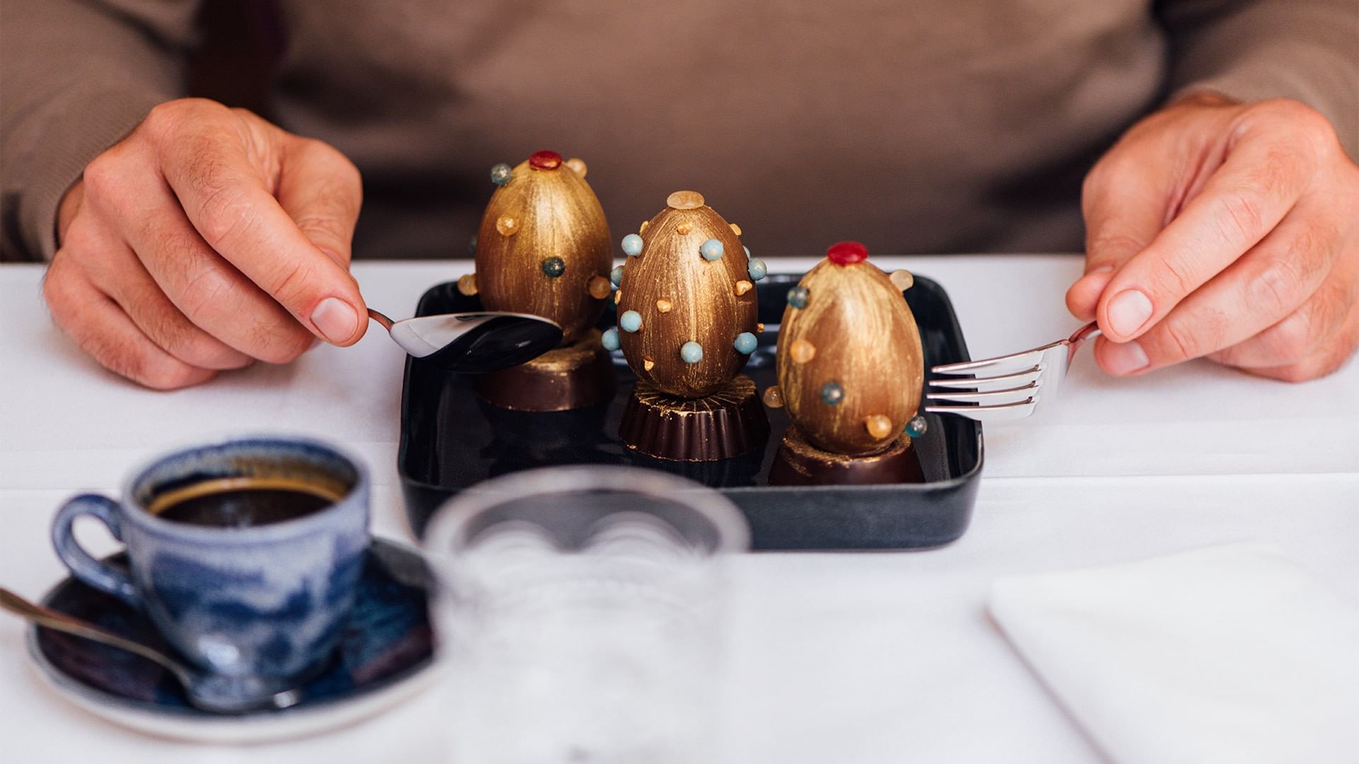 Person dining with a tray of chocolate desserts and a cup of coffee at Falkensteiner Spa Resort Mariánské Lázně