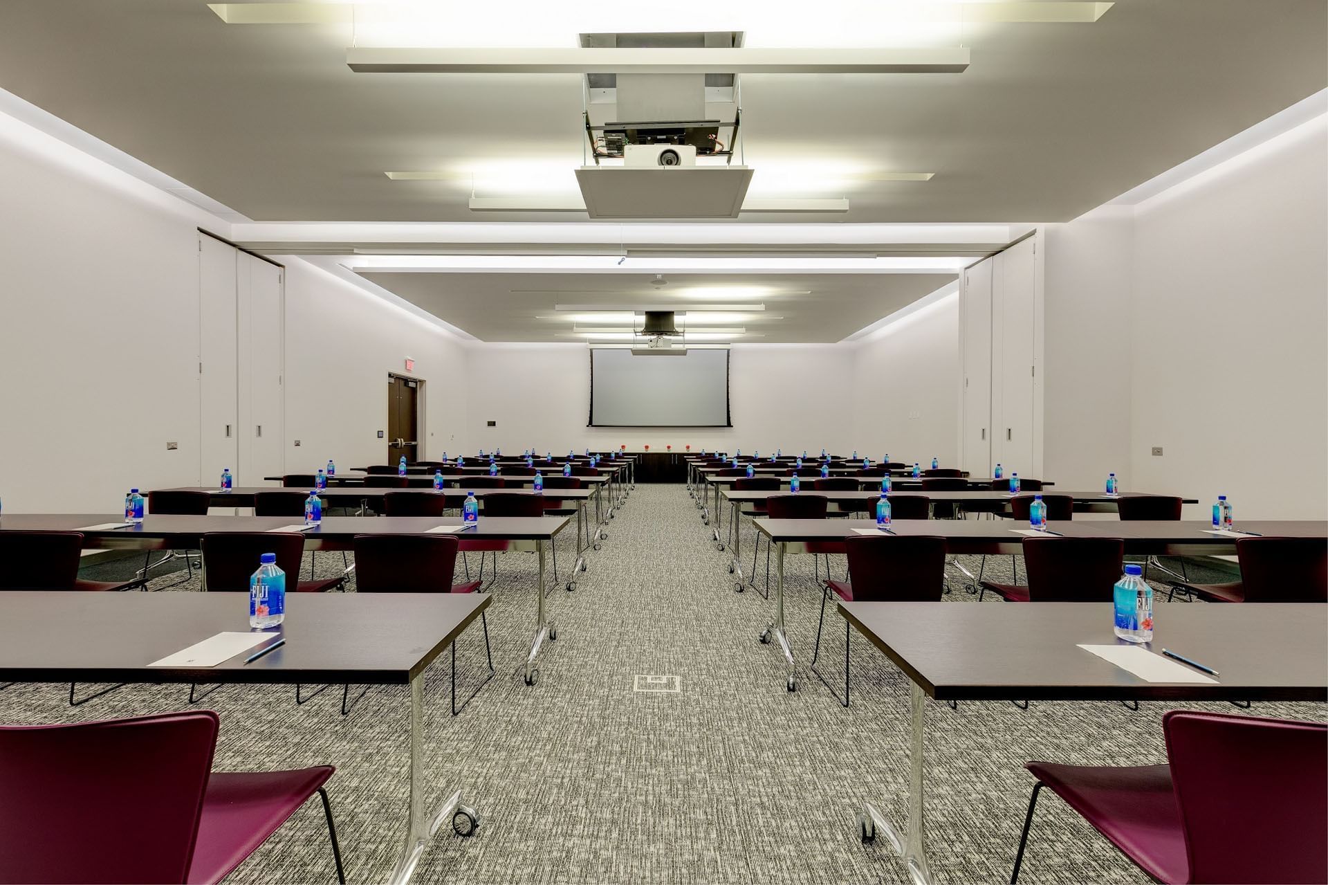 Round dining tables with white tablecloths and gray chairs set up inside a spacious Humber Park at Hotel X Toronto